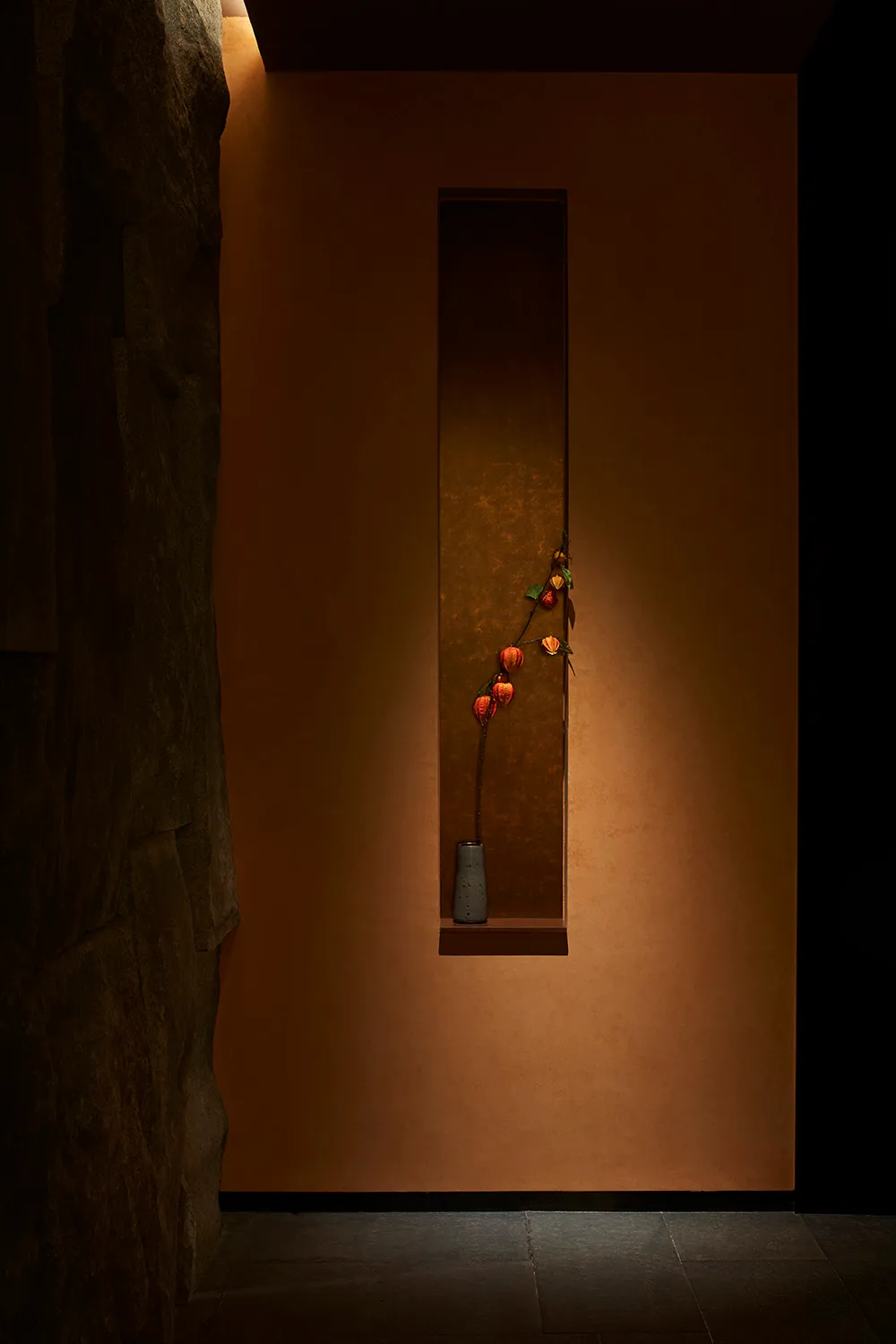 A warm and inviting interior space with a ceramic vase containing flowers and apples on a wall, surrounded by a room with a pleasant atmosphere