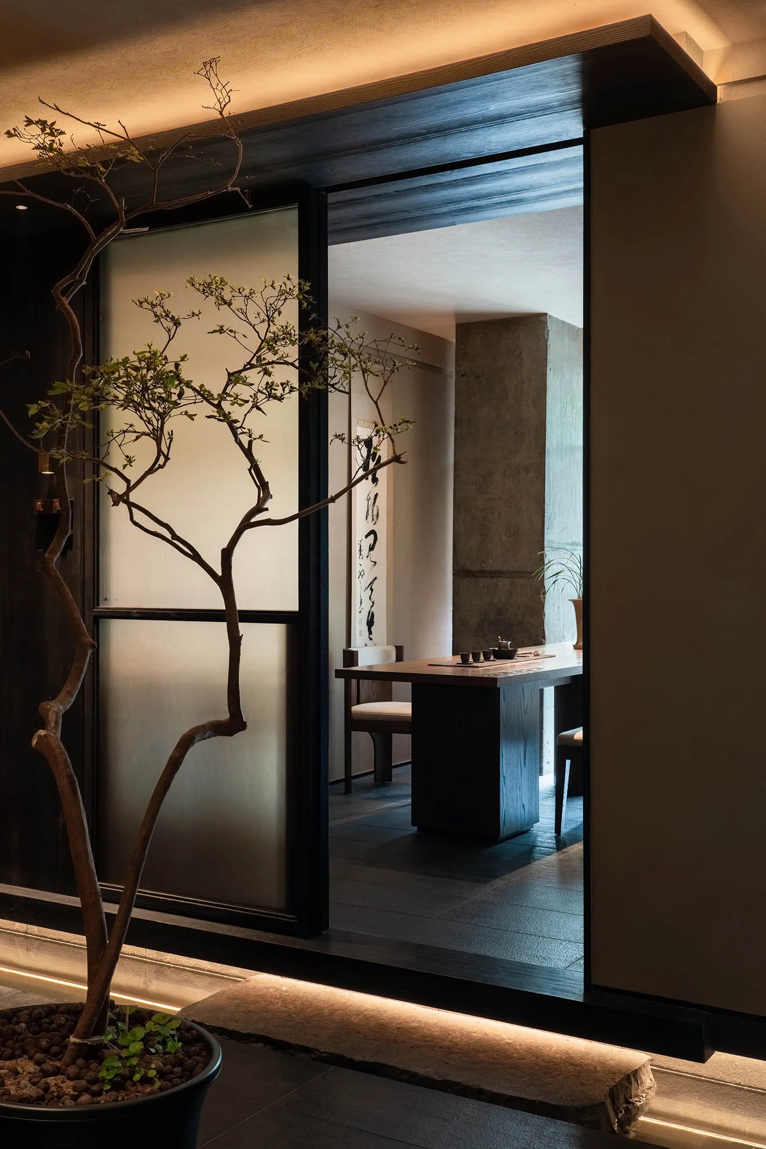 Dining room with a modern feel, featuring a dining table and chairs, a potted plant, and a large window providing natural light