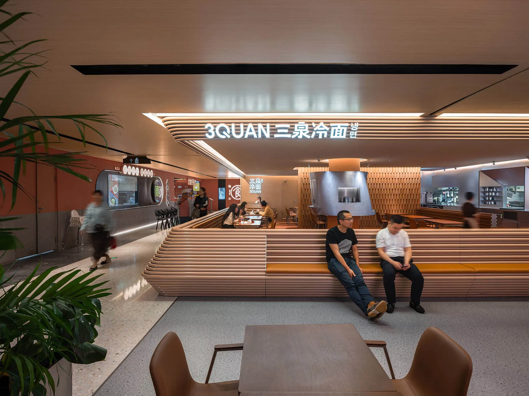 Casual restaurant interior with wooden benches and tables, people sitting and standing, warm atmosphere