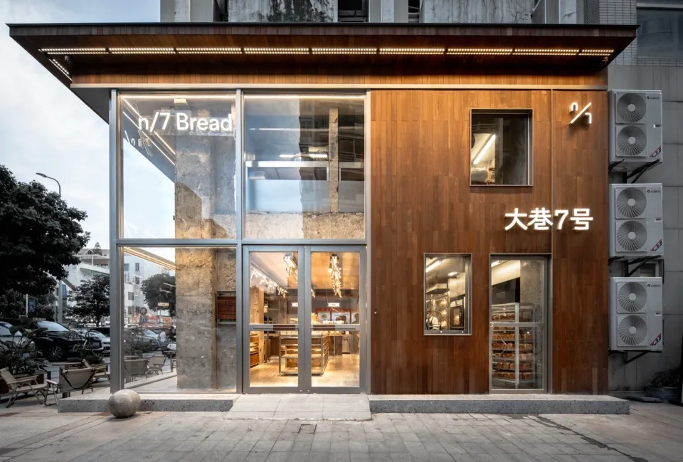 A modern bakery storefront with a wooden exterior, glass door, and interior tables and chairs, creating a welcoming atmosphere for customers