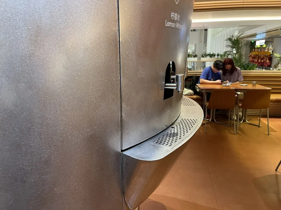 Two people standing near a metal refrigerator in a casual kitchen setting