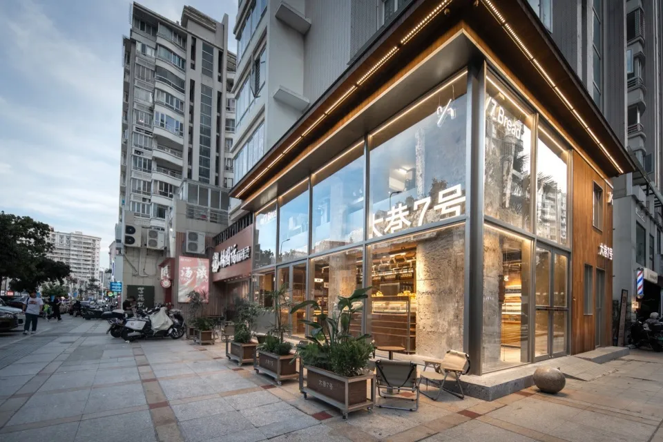 Spacious modern restaurant with glass doors, wooden and metal elements, potted plants, and a comfortable atmosphere