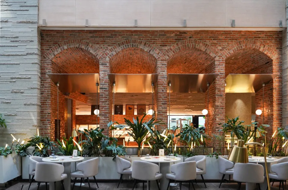 Cozy restaurant interior with brick walls, white tiles, and dim lighting, featuring dining tables and chairs