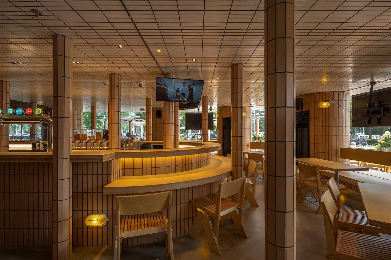 A casual bar area with a counter and three chairs, a TV screen above, and a focus on socializing and enjoying food or drinks