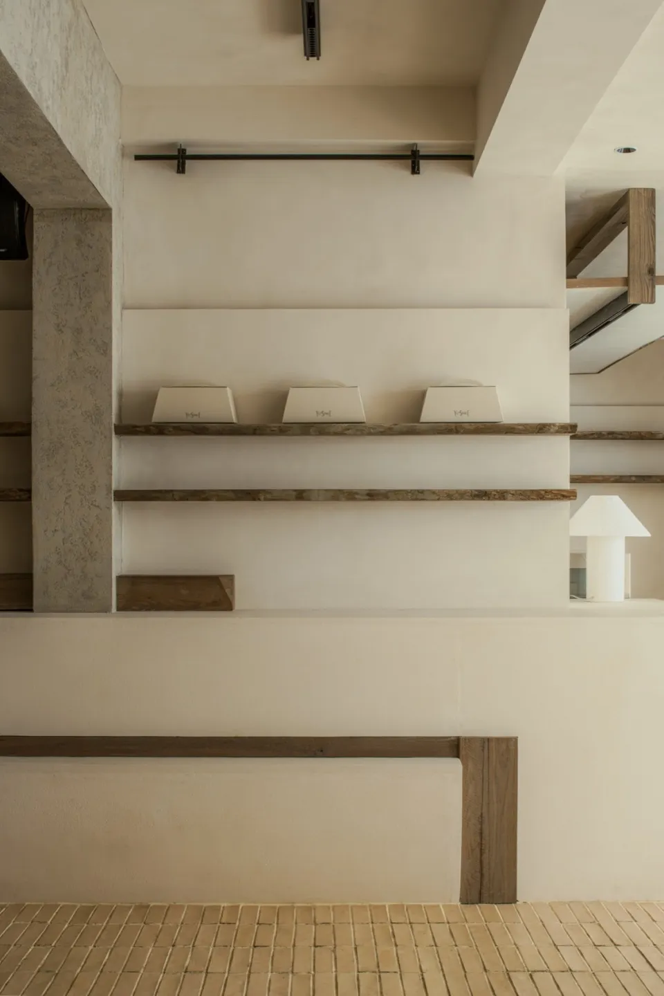 Open modern space with white walls, wooden beams, and bookshelves displaying books, creating a clean and minimalist atmosphere