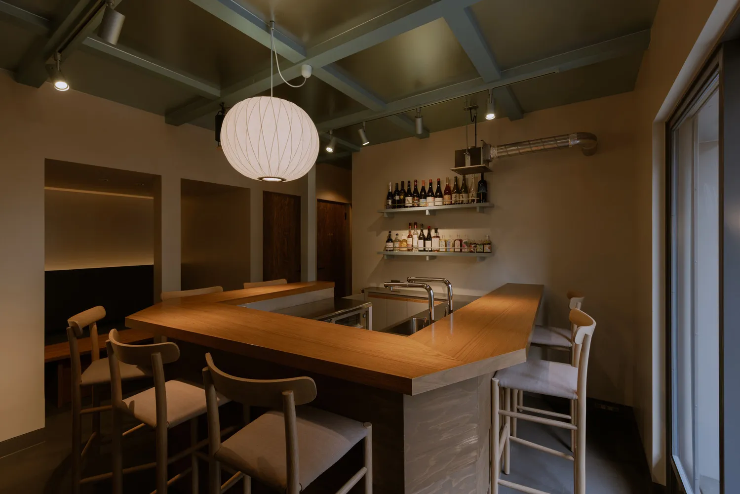 Warm and inviting restaurant space with wooden floors and walls, featuring a dining table and chairs, wine bottles, and wine glasses