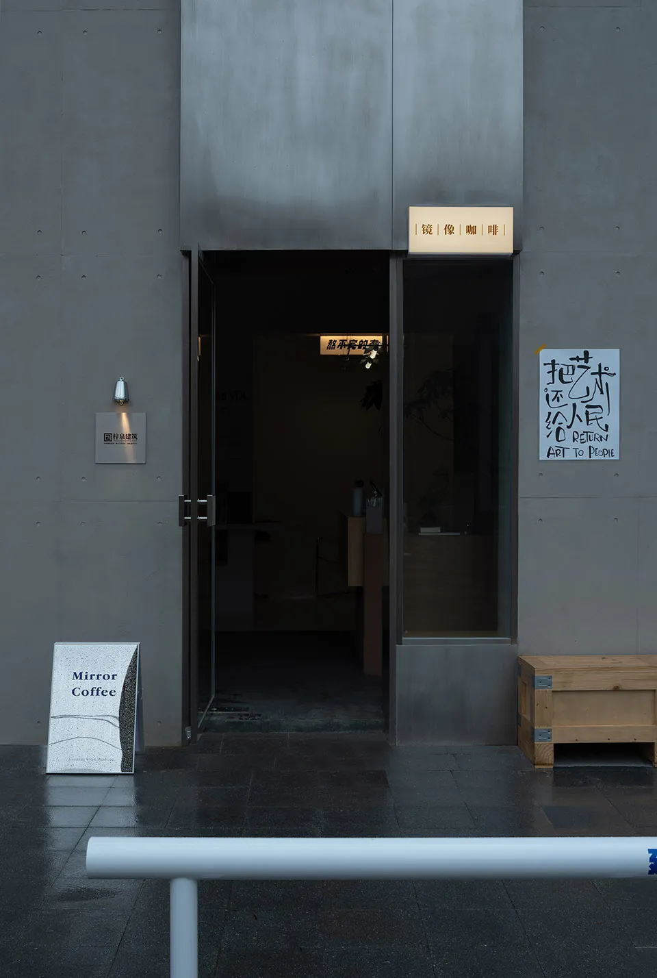 A commercial entrance with a doorway leading to a dark interior, featuring a dining table and chairs, and two signs on either side