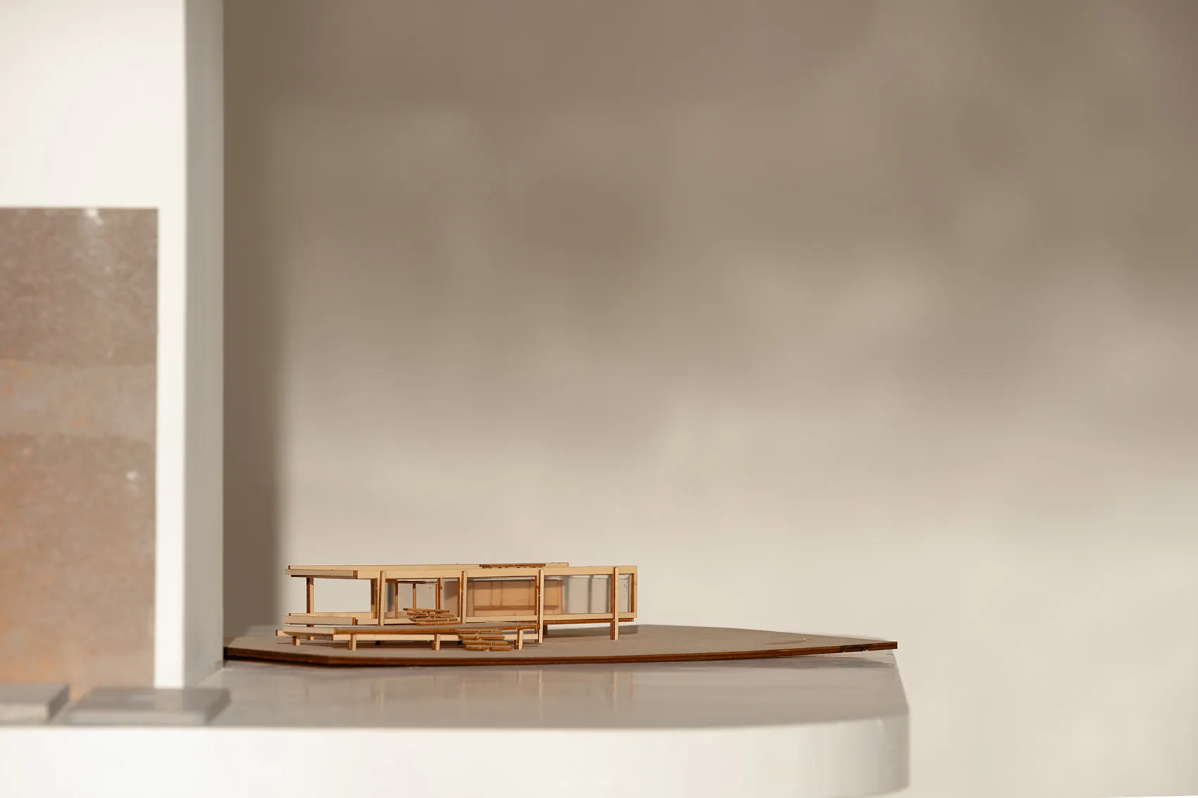 A wooden architectural model of a modern building on display, showcasing clean lines, windows, doors, and structural components, with highlighted intricate details and craftsmanship