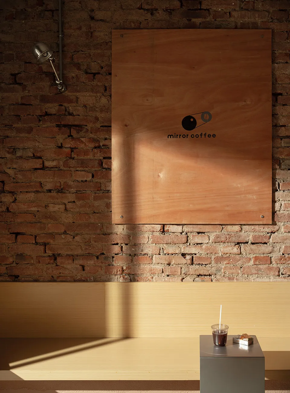Cozy coffee shop interior with a wooden countertop, brick walls, and a bottle and two cups on the counter
