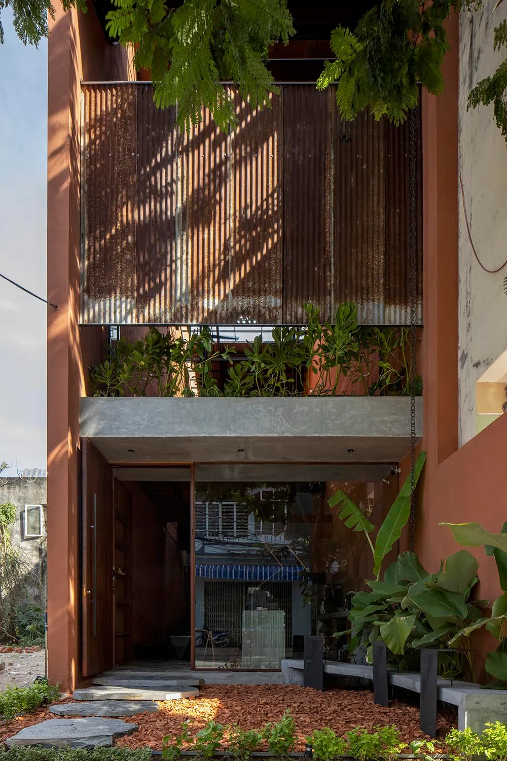 A colorful orange building with large windows and potted plants both inside and outside, creating a lively atmosphere