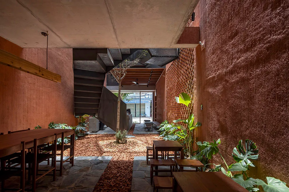 A cozy living space with a staircase, chairs, and potted plants, creating a warm and inviting atmosphere