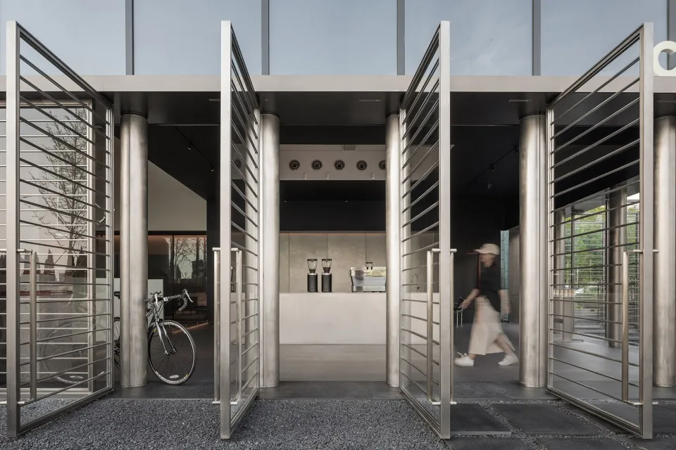 A hotel lobby with a stainless steel door, a dining table, chairs, and a bicycle, surrounded by welcoming and elegant atmosphere
