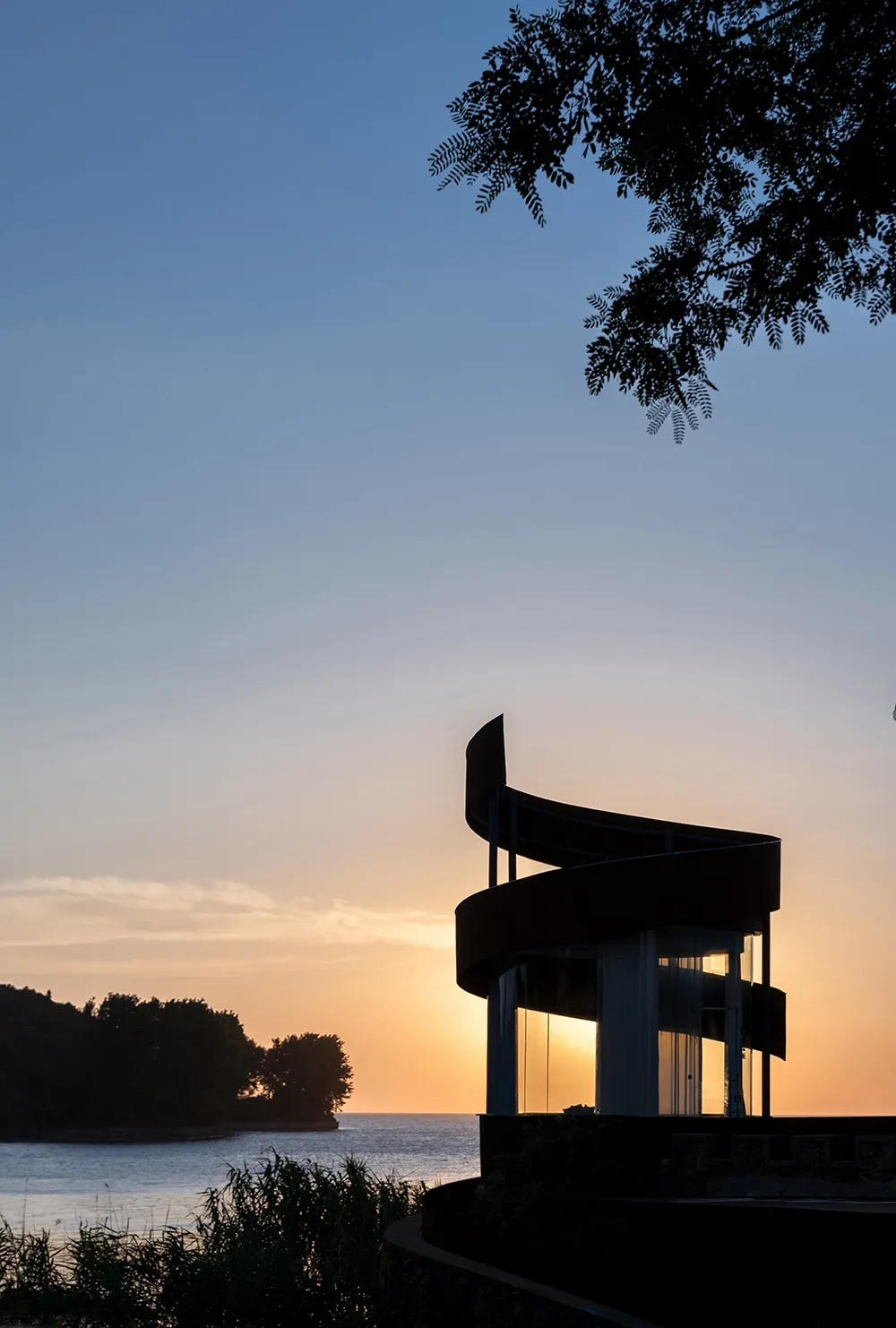 A modern building with a boat-inspired design element, set against a warm sunset backdrop, with a concrete exterior and a sense of grandeur and innovation
