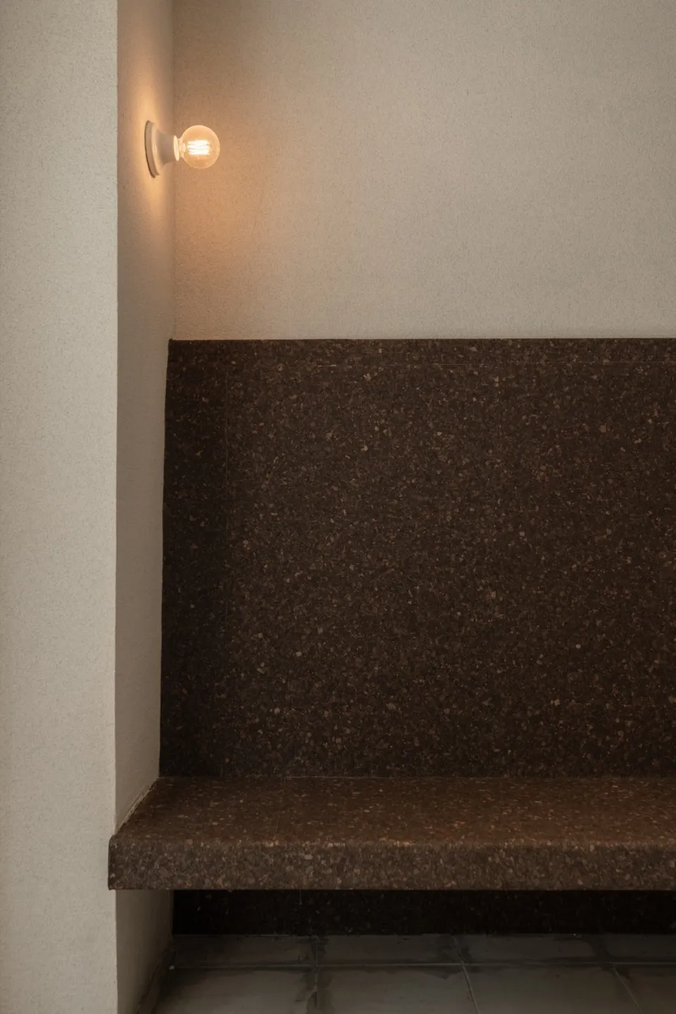 Modern bathroom with brown tiles on the walls and floor, featuring a sink area, toilet, and two lights