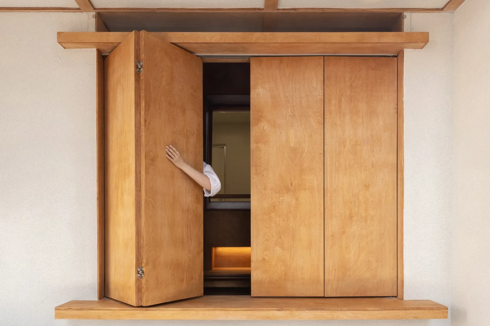 A person stands in an open doorway of a rustic wooden cabin, peeking through with a sense of curiosity and anticipation