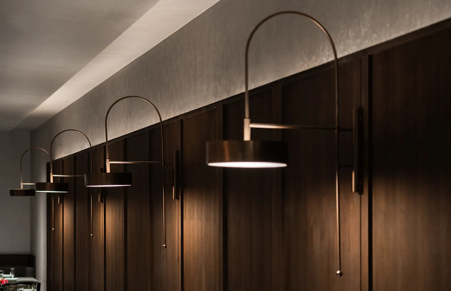 A dimly lit hallway with wooden walls and ceiling, lit by three pendant lights at varying heights