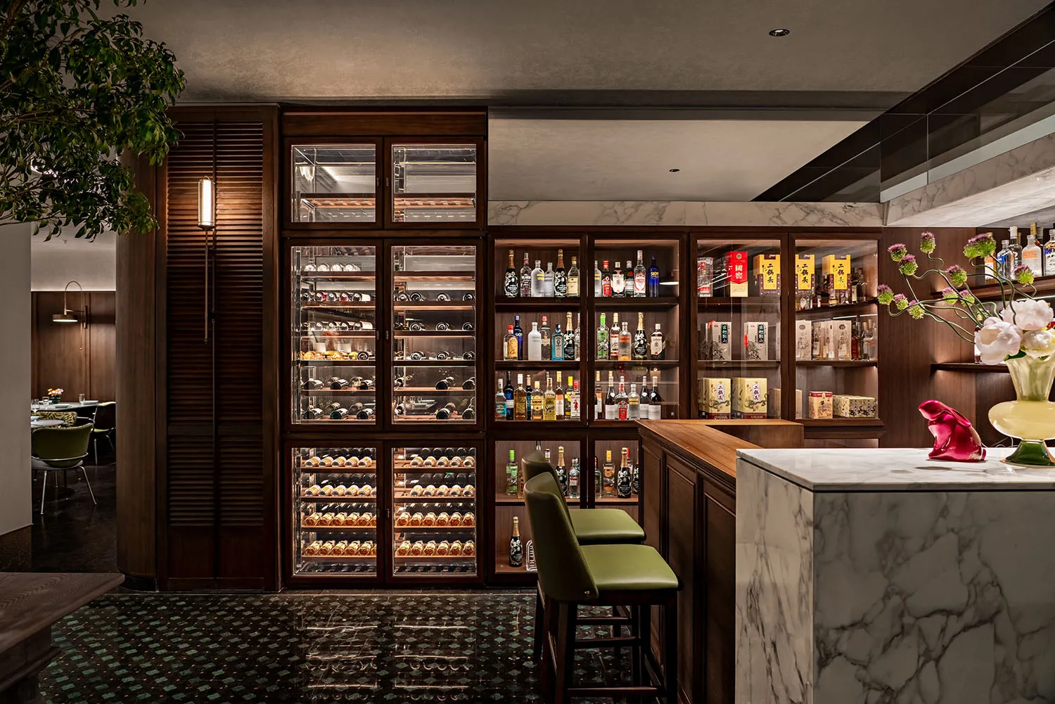 A cozy bar area with a display case of liquor bottles, multiple chairs, and a comfortable seating arrangement