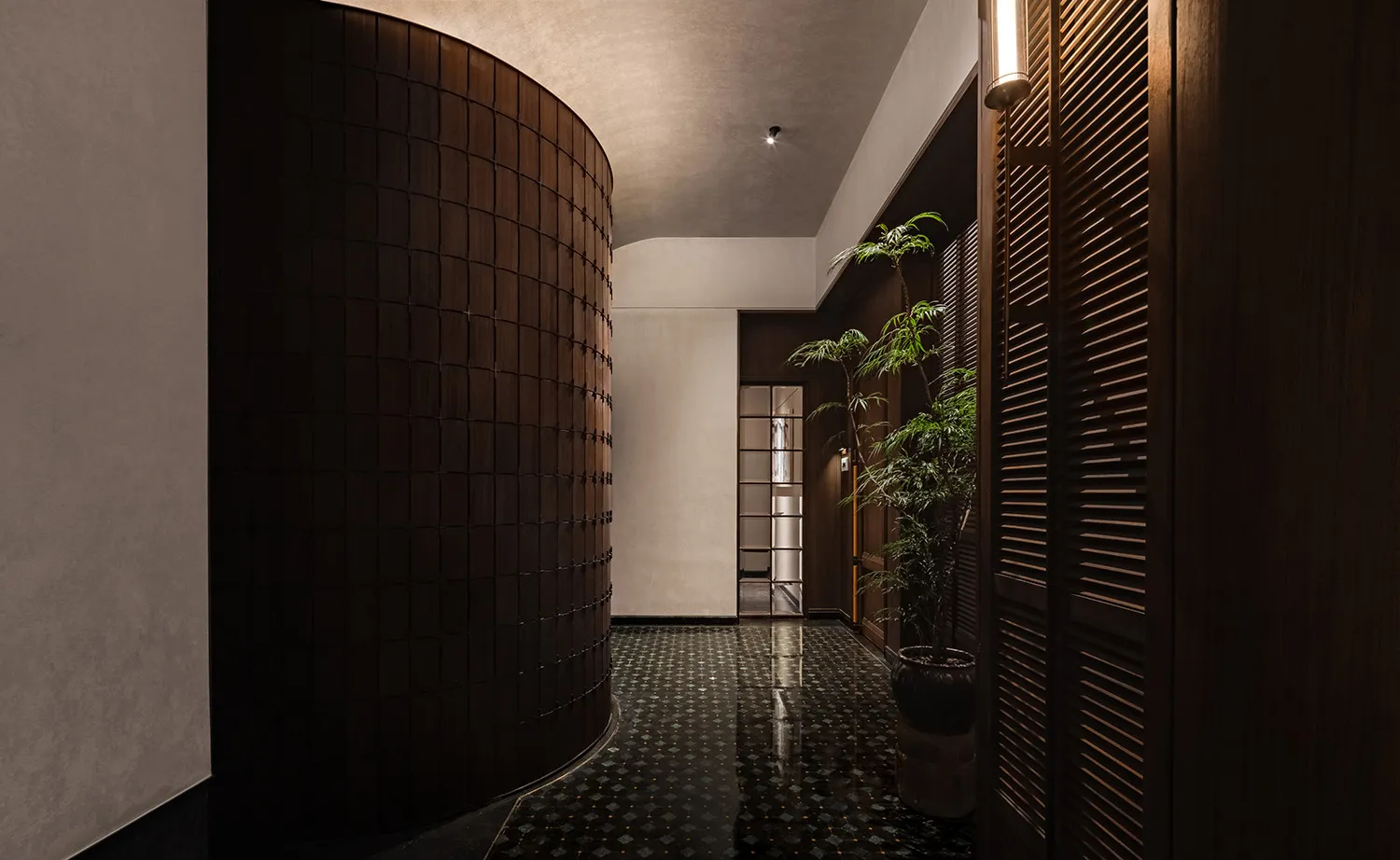 寧靜溫馨的走廊，配有黑白棋盤磚地板、兩盆盆栽與一張椅子