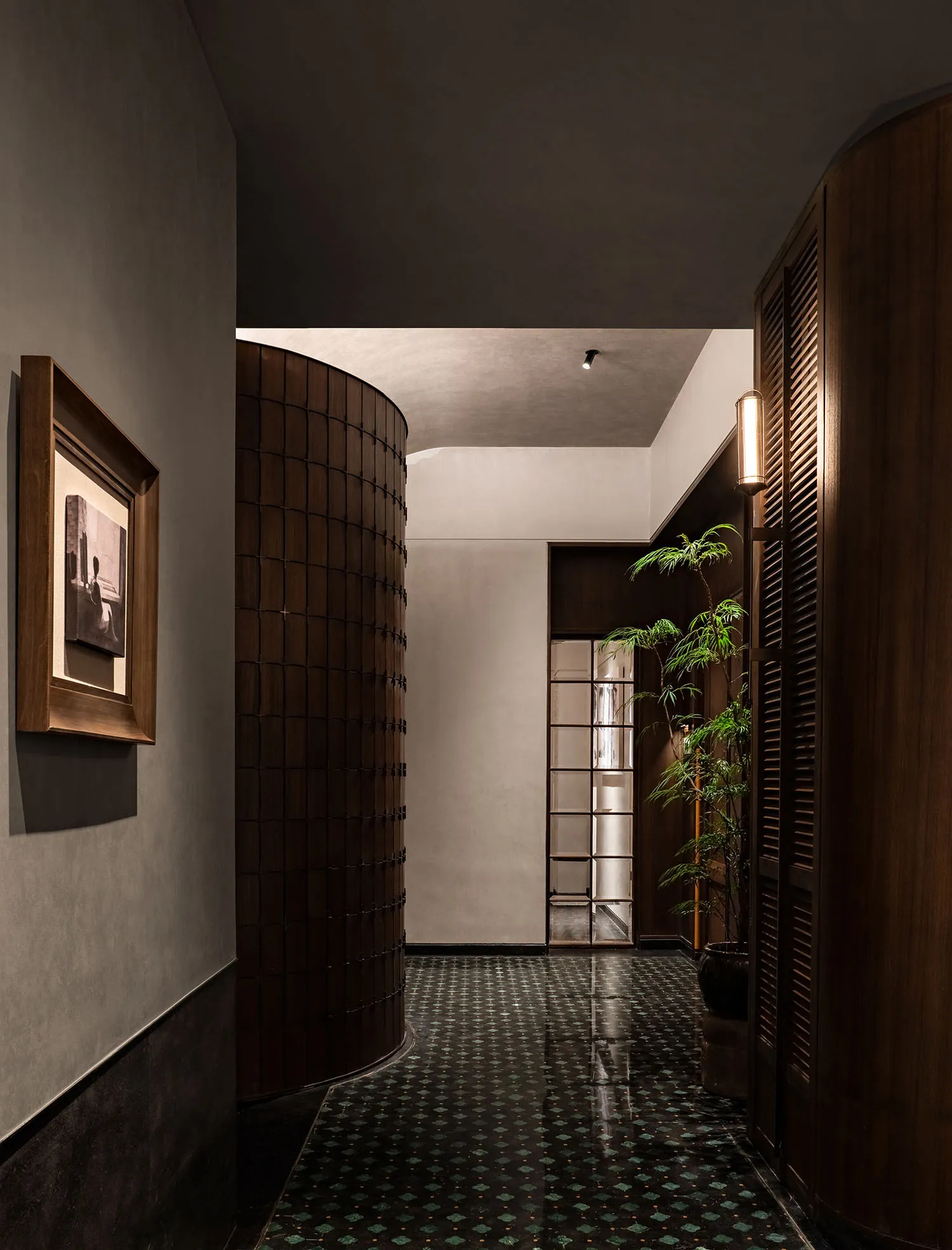 A calm and inviting hallway with a tile floor, wooden and glass doors, and two potted plants adding greenery to the space