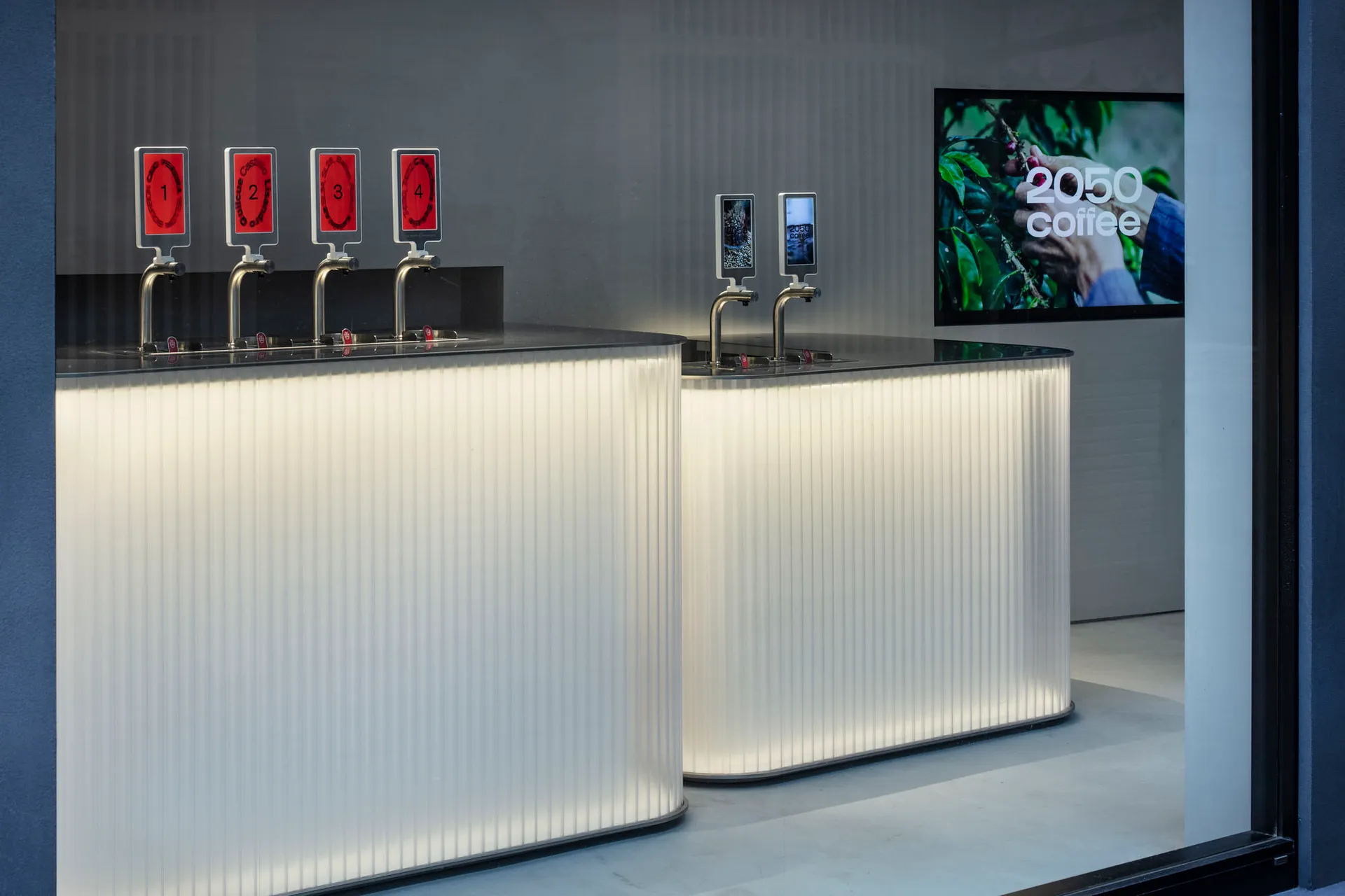 Modern bar area with white countertops, beverage dispensers, and cups, set in a stylish and upscale environment