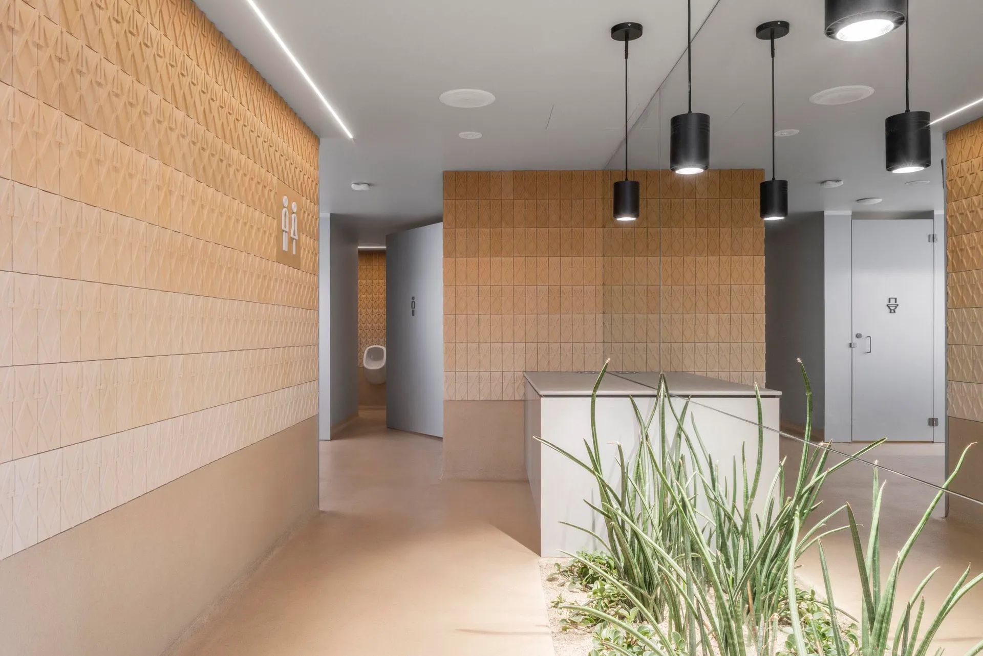Modern bathroom with two sinks, a toilet, and a tiled wall and floor, suggesting a clean and modern appearance