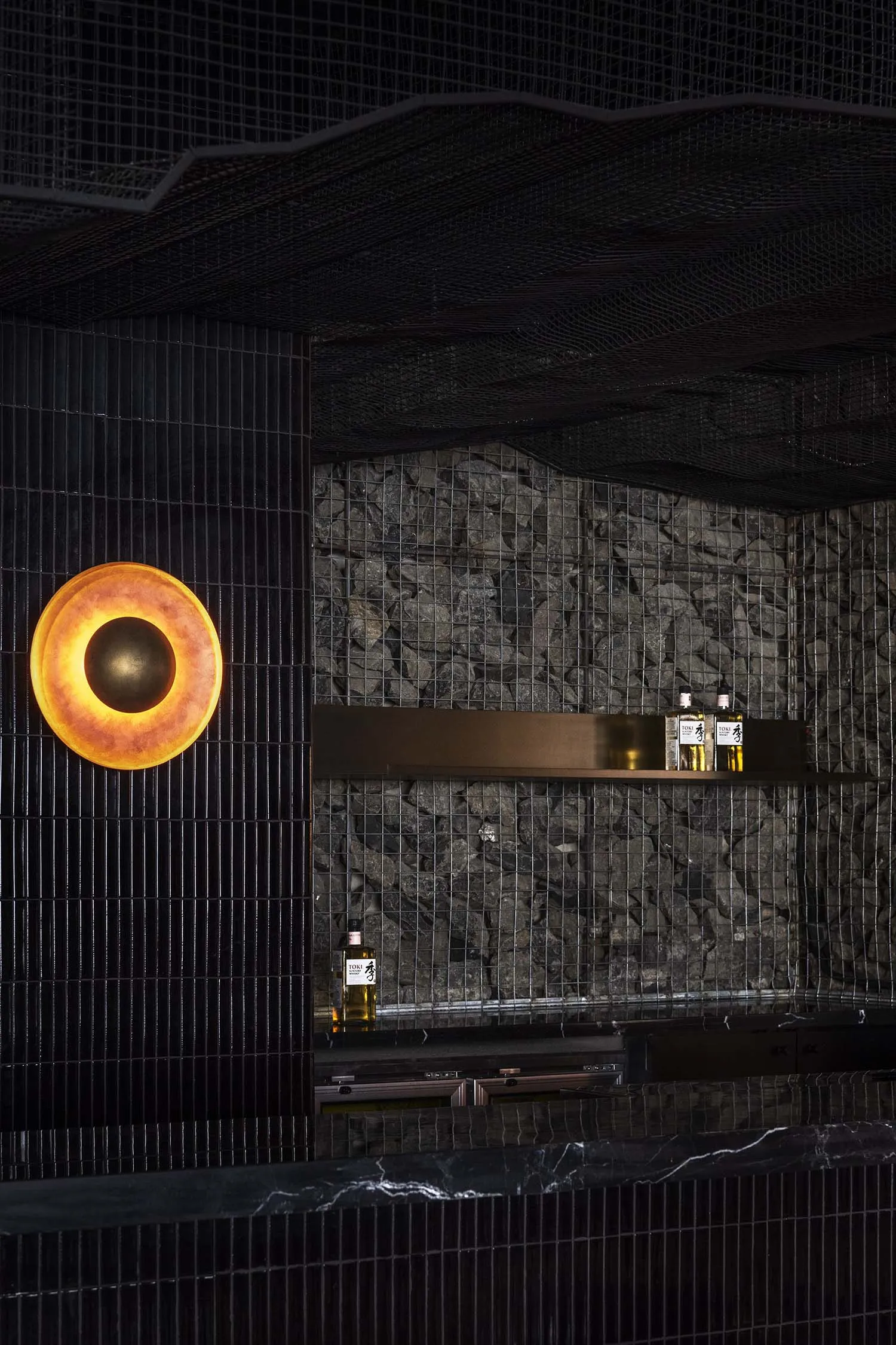 Elegant bar area with a stone wall, two bottles on the countertop, and a sophisticated atmosphere