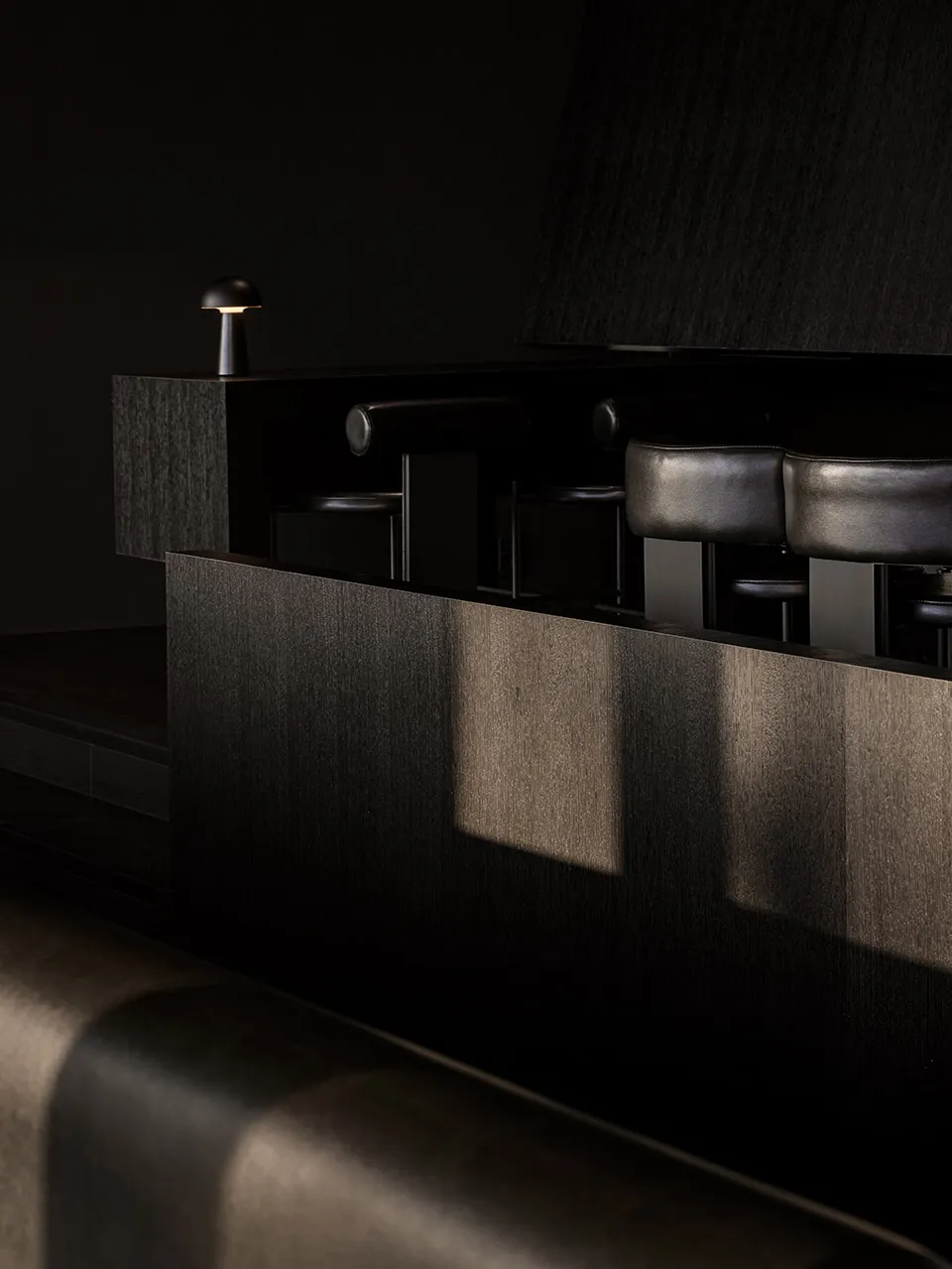 Dark bar area with black leather chairs and couches, intimate and cozy atmosphere