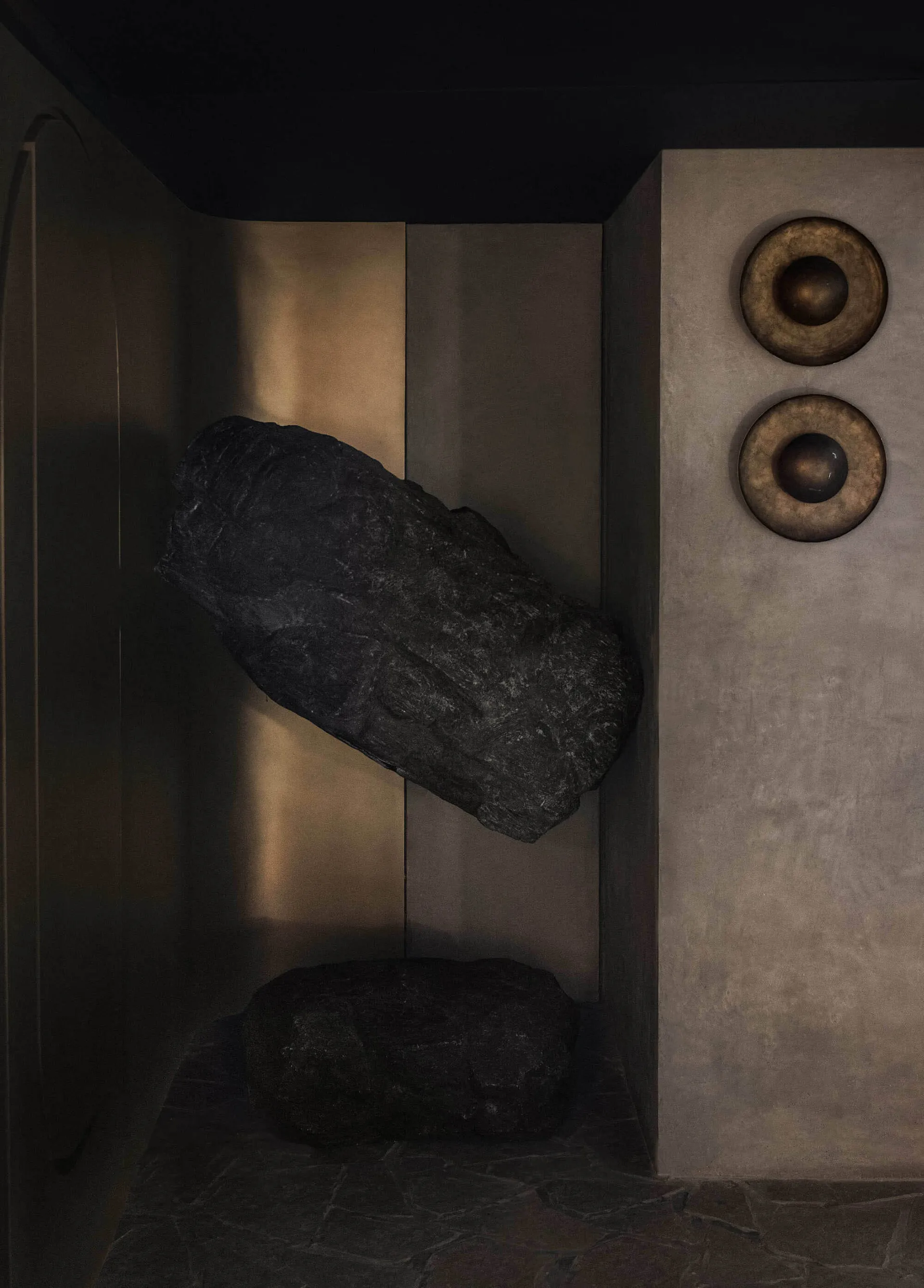 A dark room with two large rocks and three smaller rocks, along with four round objects, scattered throughout the space