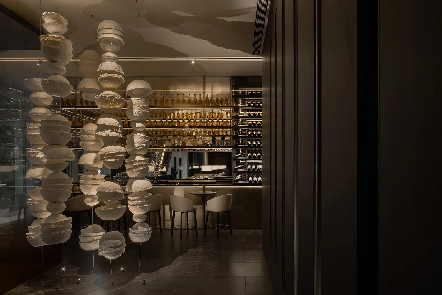 Elegant wine bar with a chandelier, dining table, and comfortable seating for patrons to enjoy drinks and socialize