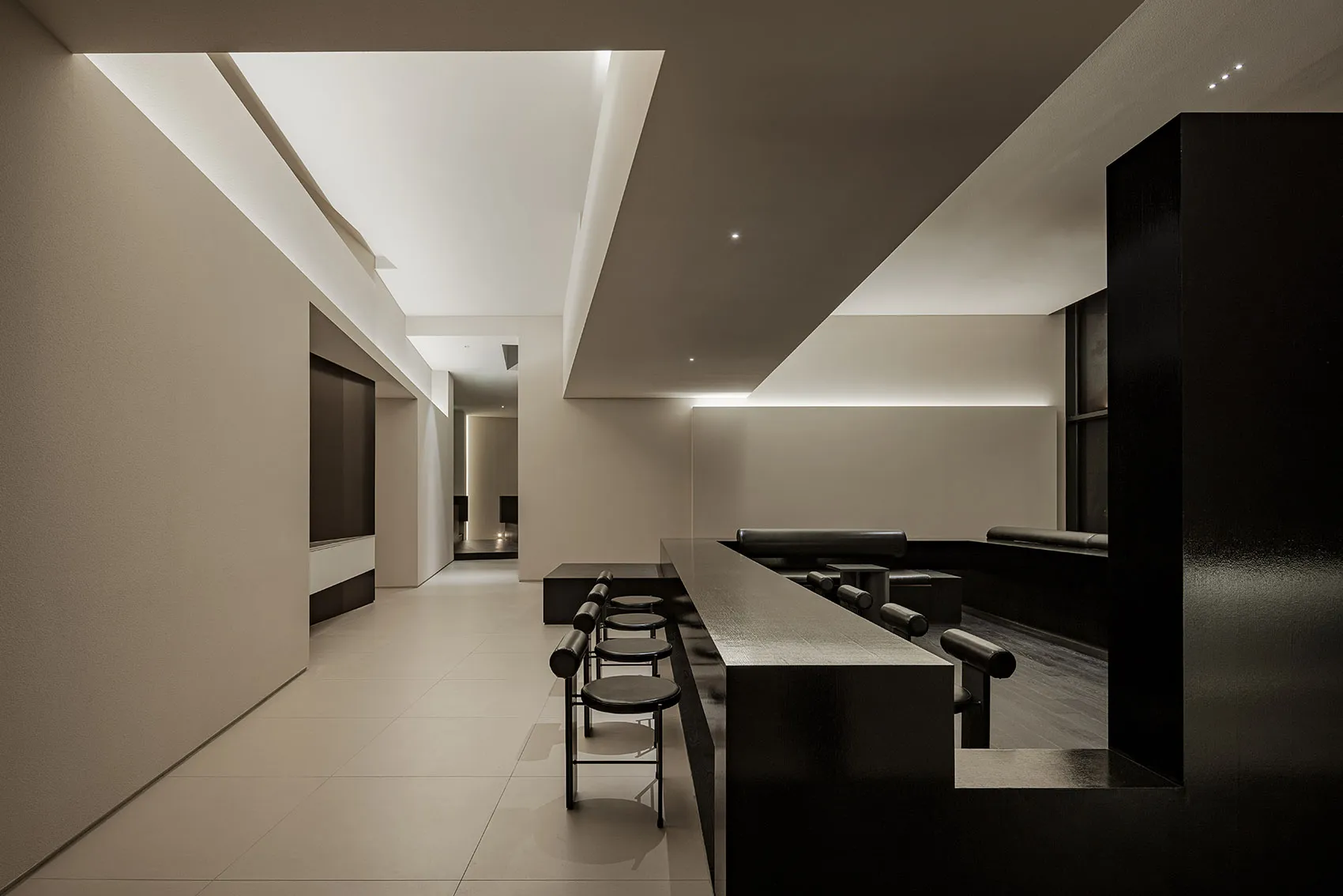 Modern bar area with a black countertop, dining table, and chairs, providing seating options for guests