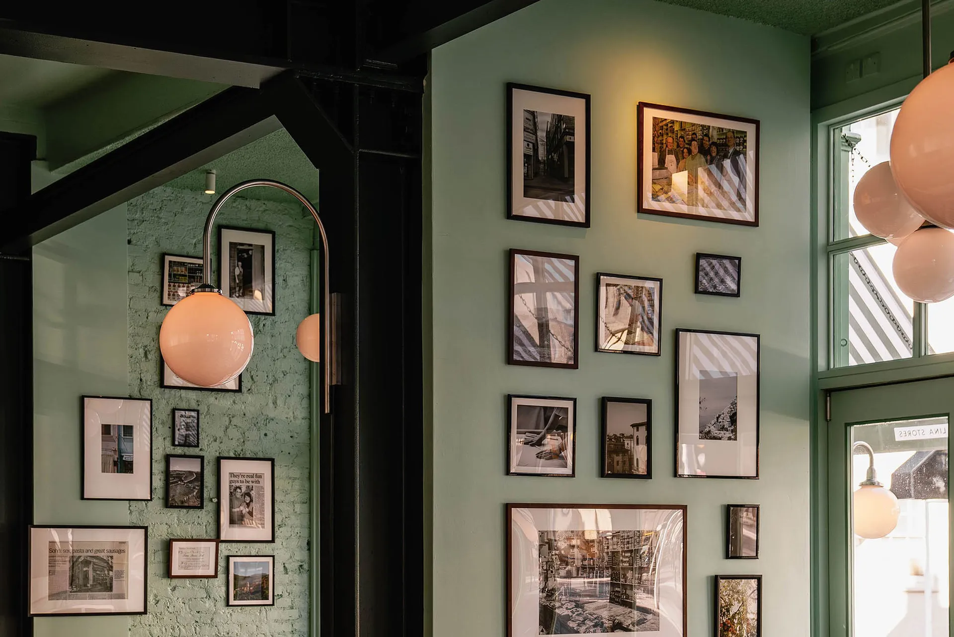 A restaurant wall with a gallery of framed pictures in various sizes, arranged to create a decorative display on a green wall
