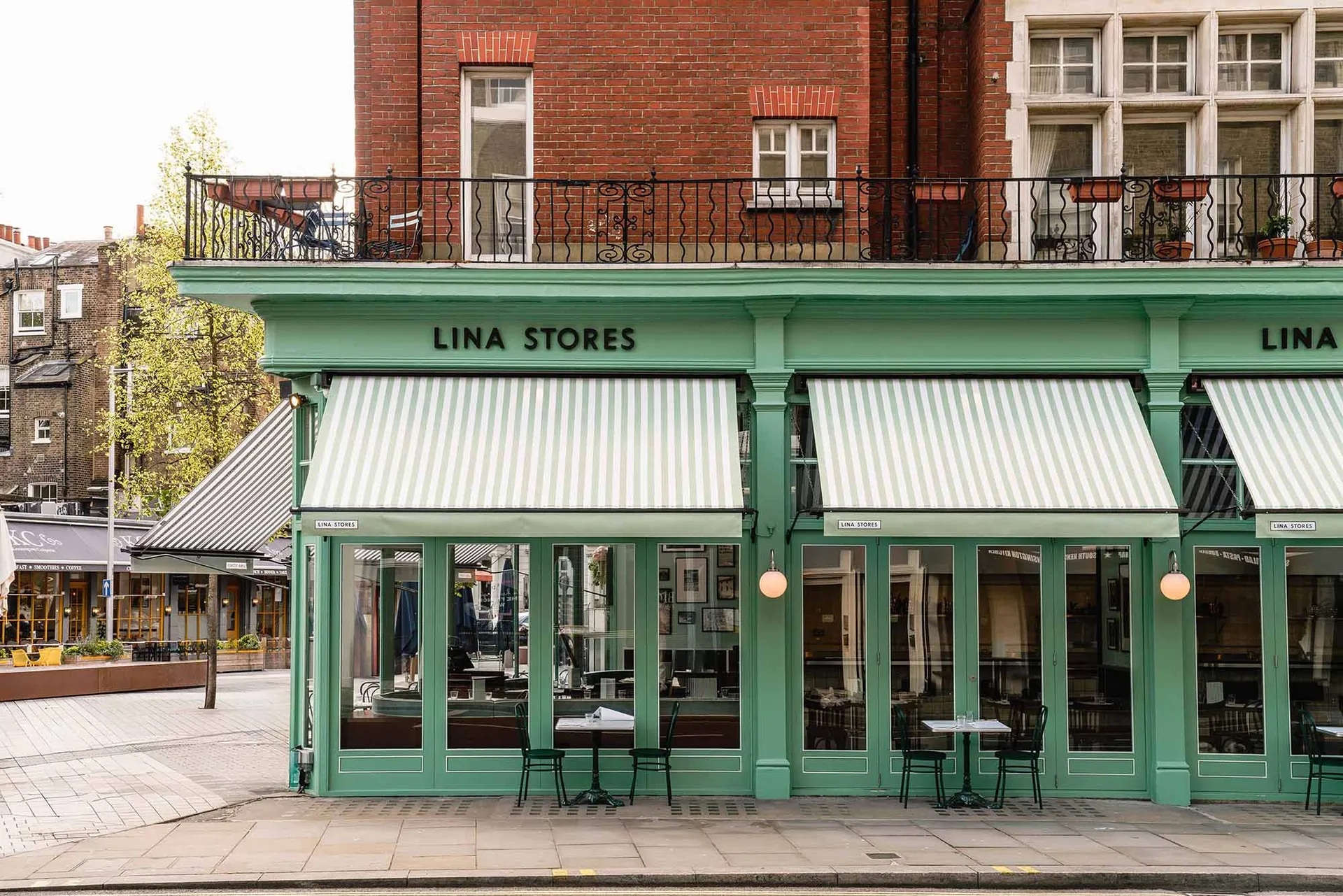 A casual storefront with outdoor seating area featuring chairs arranged around the exterior of the building, creating a welcoming atmosphere for customers