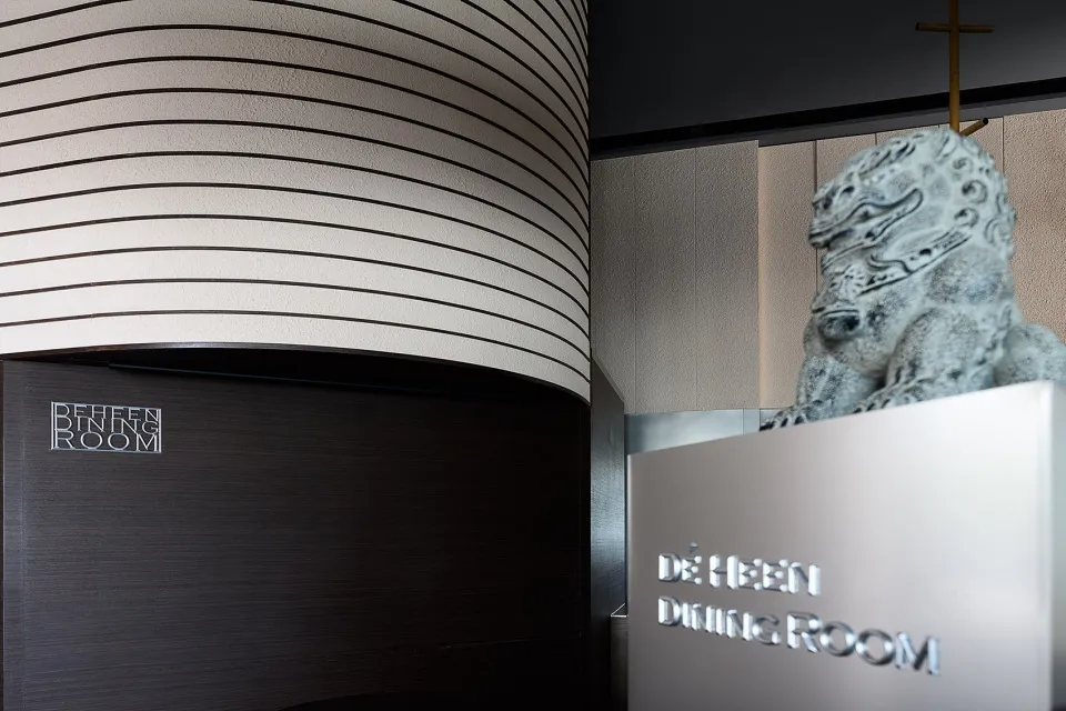Elegant interior design featuring a large dragon statue in front of a striped wall, with a sophisticated atmosphere reflecting Asian cultural influence