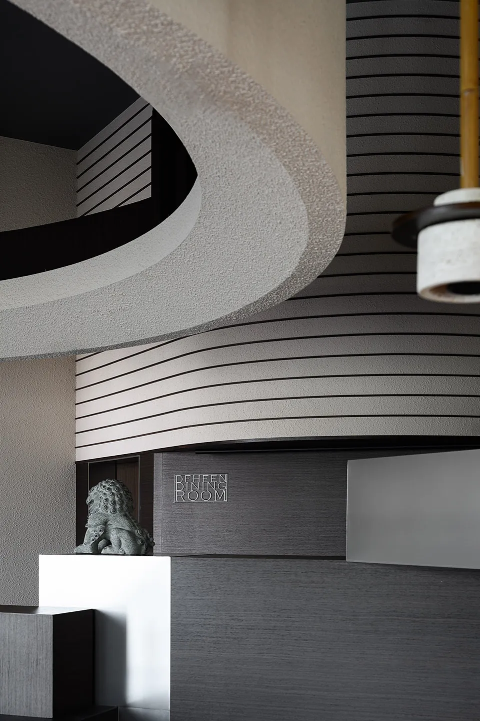 A modern room with a curved ceiling, grey walls, and two large hanging lights, creating a bright and inviting atmosphere