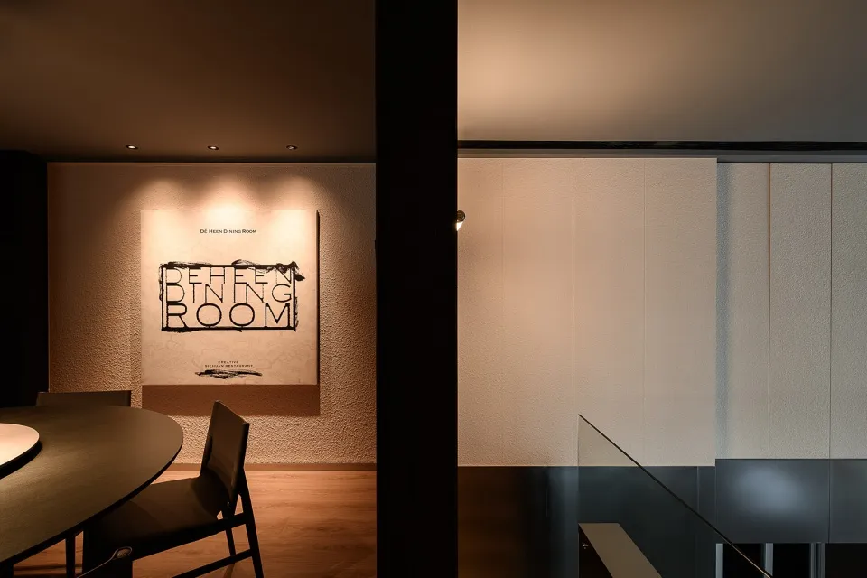 A modern dining room with a large table, chairs, a couch, and white walls, creating a clean and bright ambiance