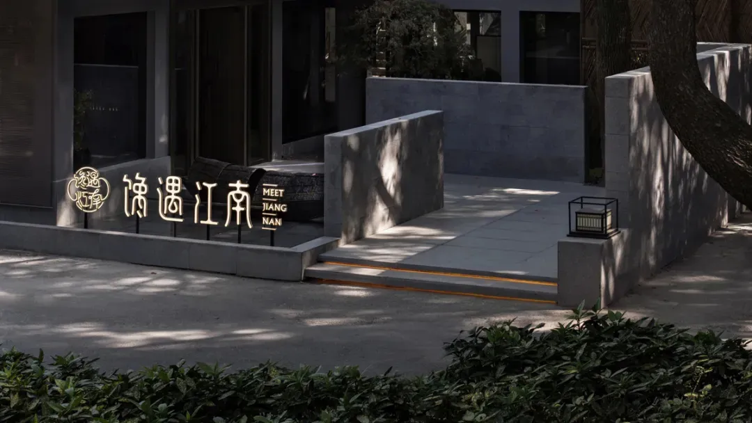 A modern Asian restaurant with a large stone wall, seating areas, potted plants, and a well-designed atmosphere