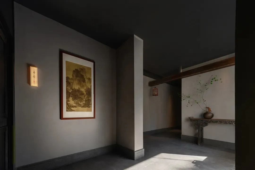 Empty room with a gray wall, black ceiling, and stone floor, featuring two framed artworks on the wall in a calm and quiet atmosphere
