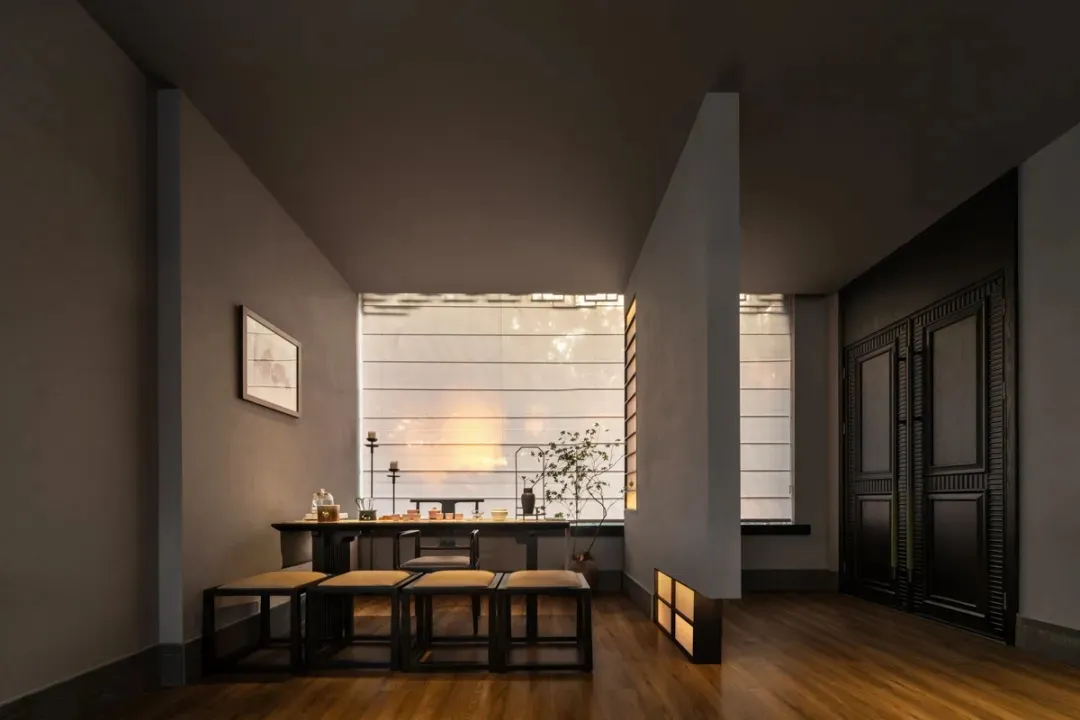 Empty modern living room with a dining table, chairs, potted plants, and decorative bottles, creating a cozy atmosphere