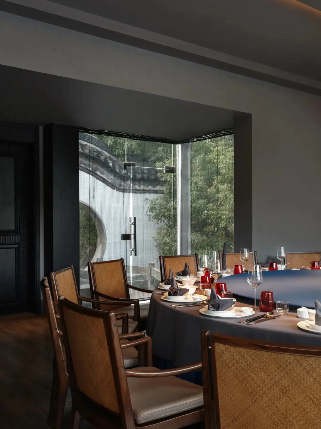 Elegant Asian restaurant interior with a large dining table set with various items and vases, surrounded by chairs