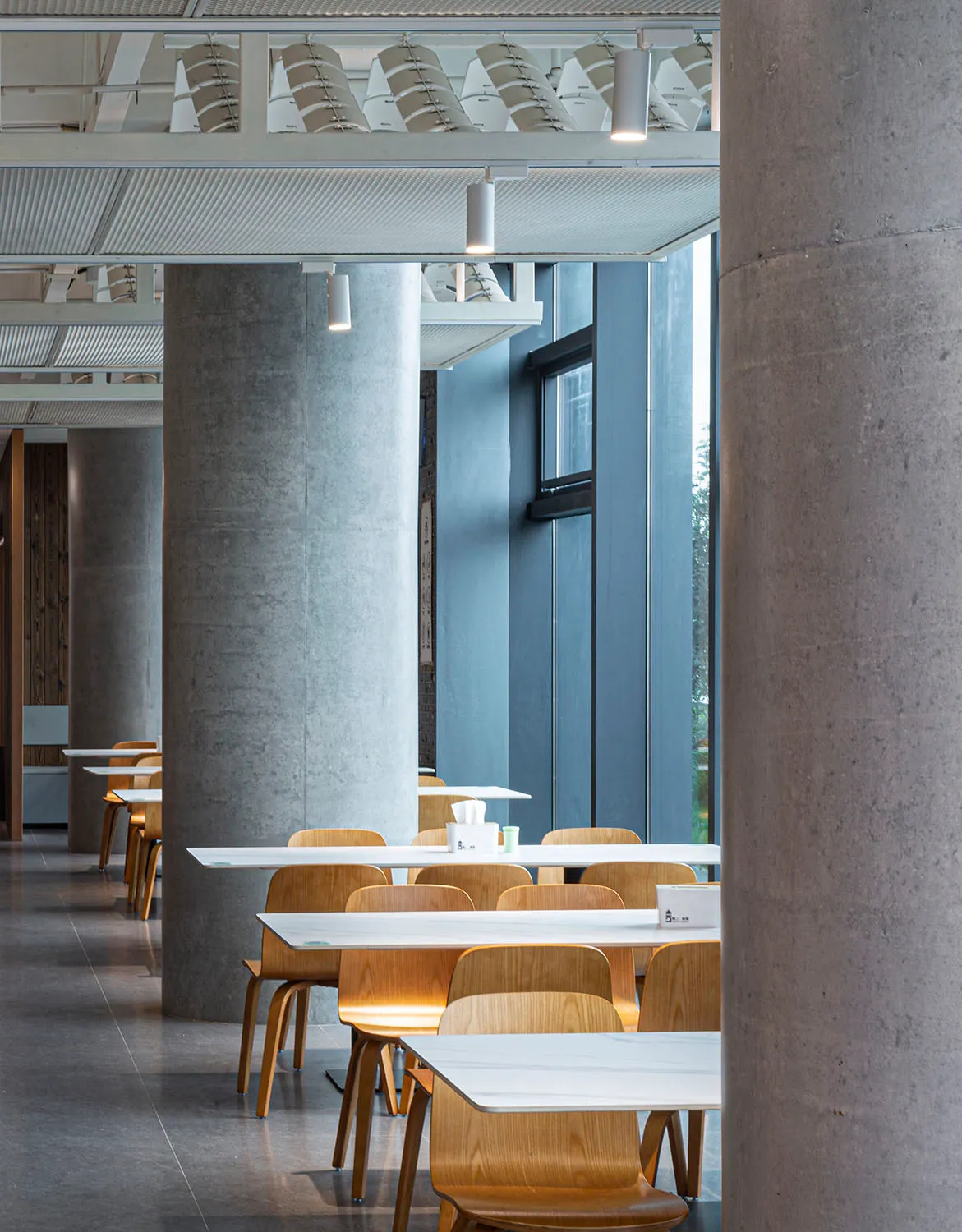 A modern dining area with multiple white tables and chairs, cups, and a spacious atmosphere