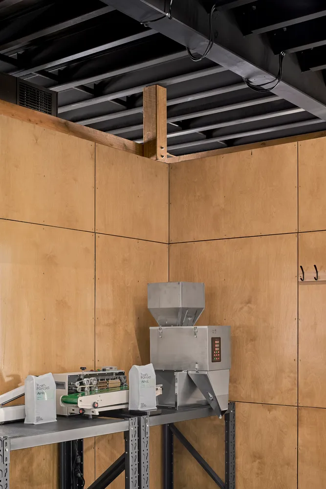 Industrial workspace with a large machine and smaller machines on either side, surrounded by wood panel walls