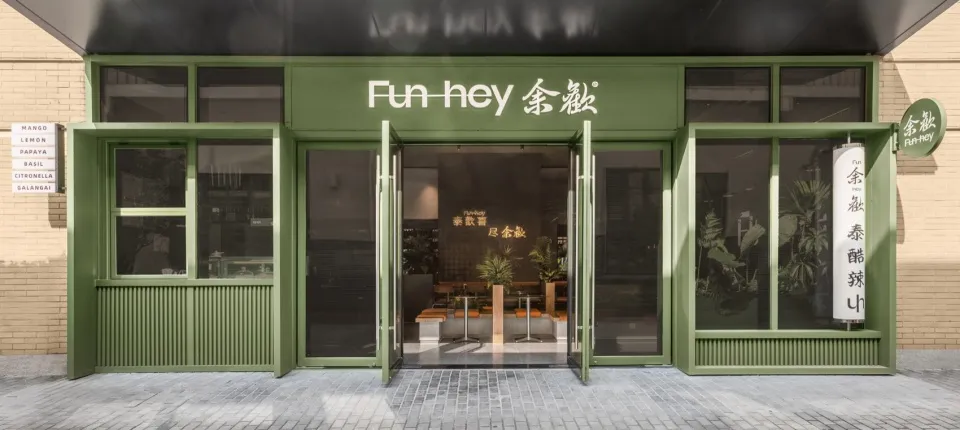 An inviting Asian restaurant with green walls, wooden furniture, and potted plants, creating a comfortable dining atmosphere