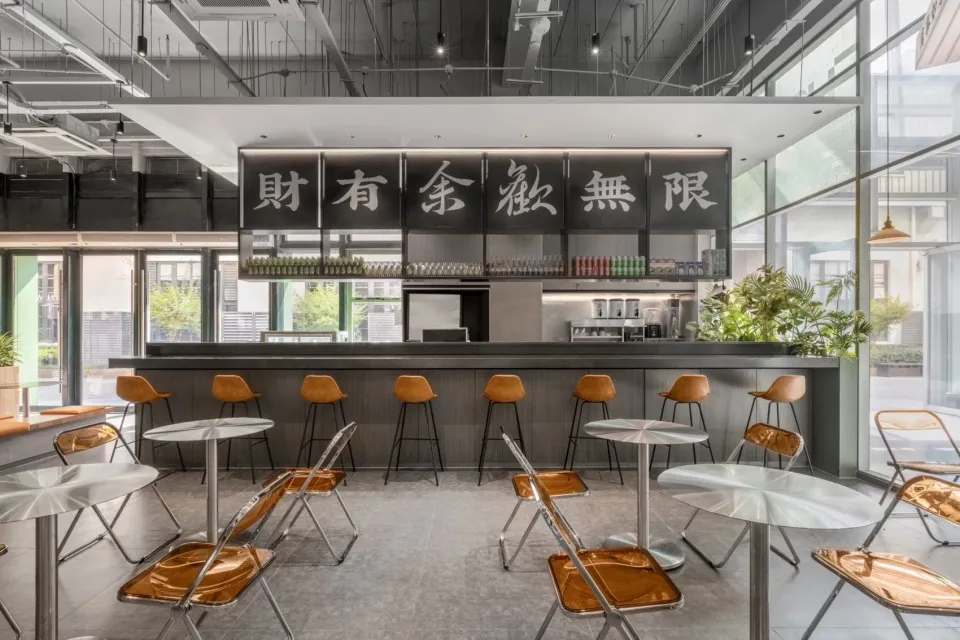 現代亞洲餐廳，灰色牆面、黑色點綴、餐桌椅與吧台區，自然光與人工照明營造明亮氛圍