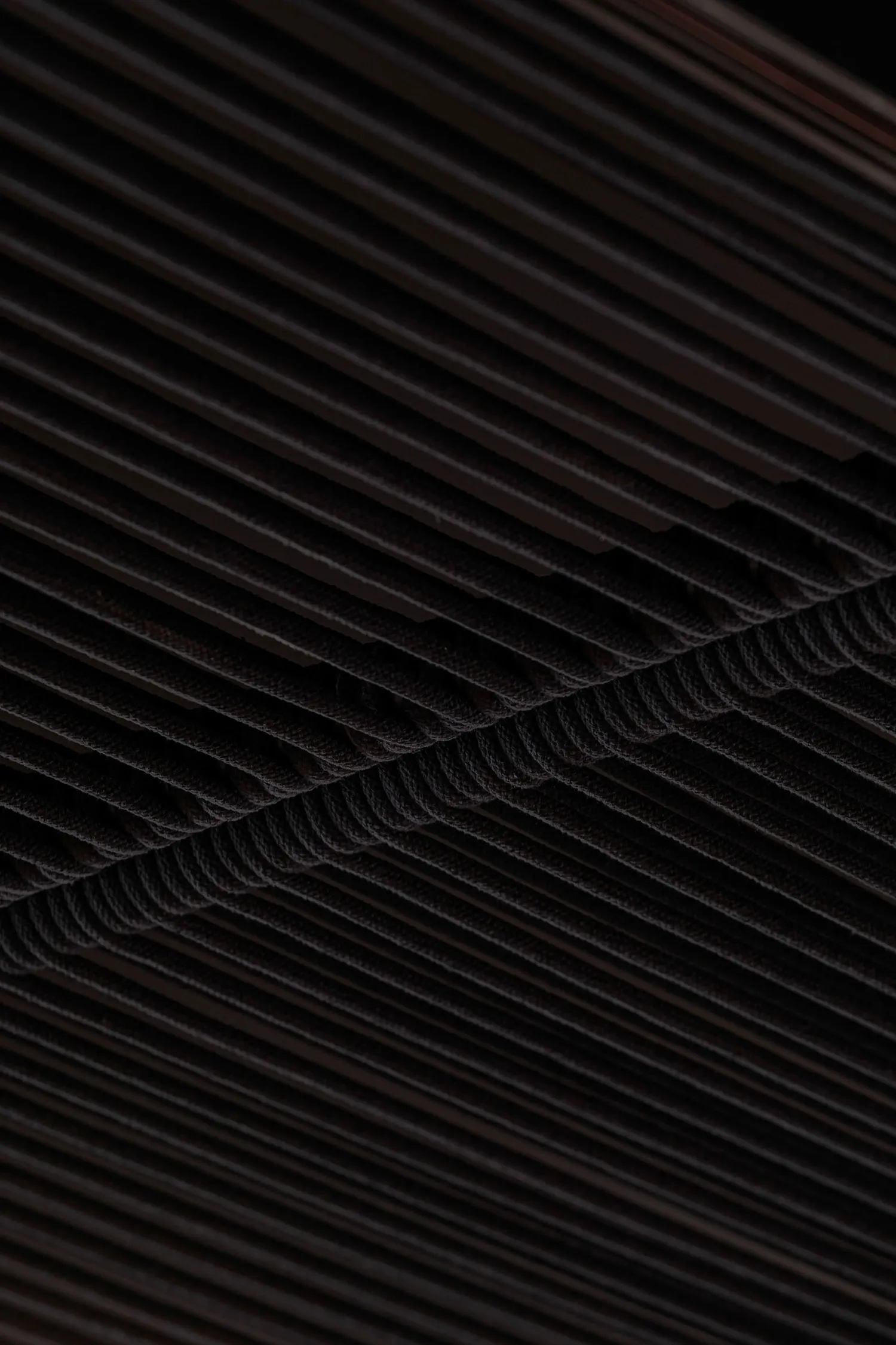 Dark industrial space with a black metal ceiling featuring multiple rows of ropes, creating a striking visual effect