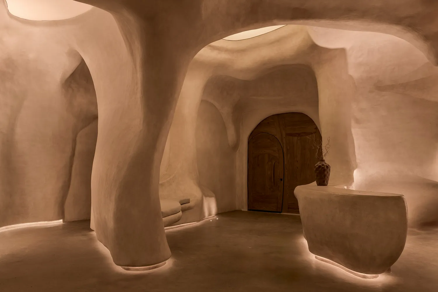 Cozy interior space with a large archway, sink area, bench, and potted plants, creating a welcoming atmosphere