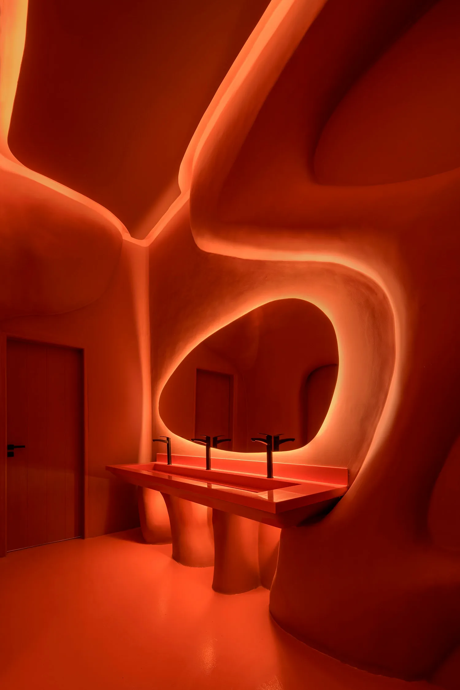 A bathroom with two sinks, red walls, and a bottle near one of the sinks, giving a clean and well-maintained appearance