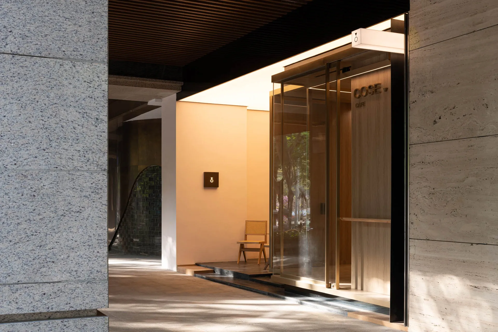 Modern entrance with a glass door, a large window, and two chairs for seating, set in a well-lit and functional space
