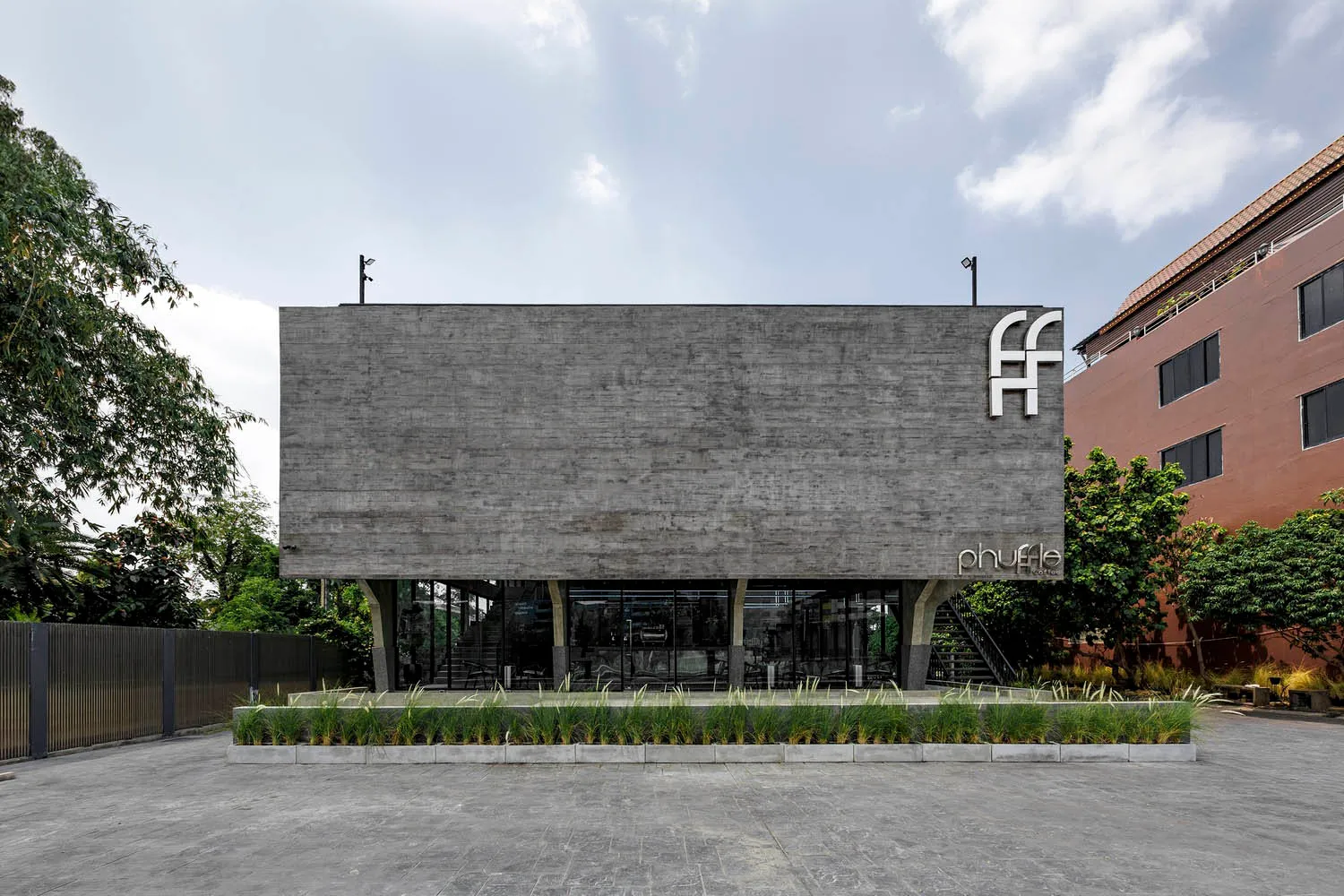 Modern building with a large gray concrete wall featuring windows with curtains, set against a bright daylight background