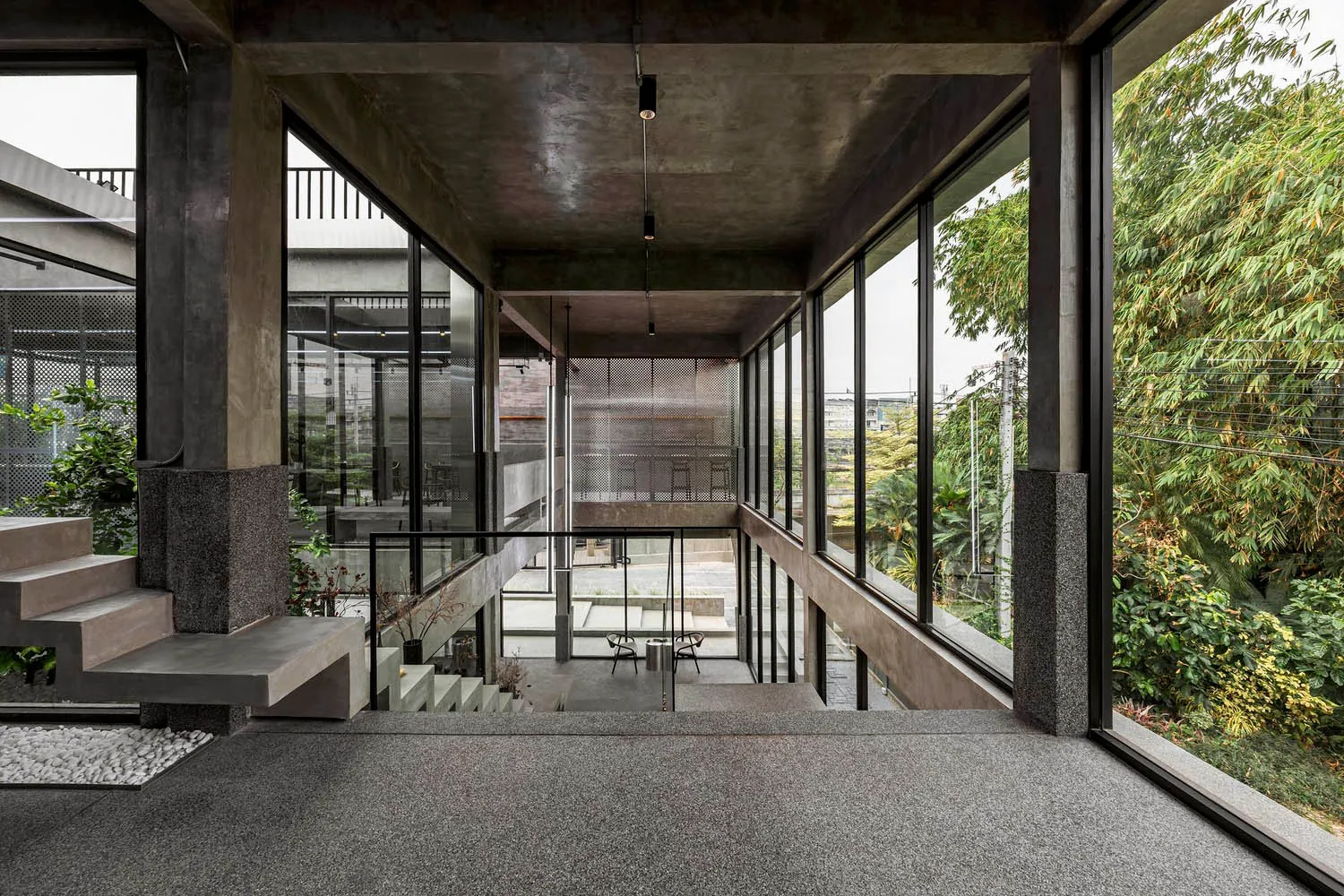 Open living space with a staircase, large windows, and potted plants, featuring a bright and inviting atmosphere