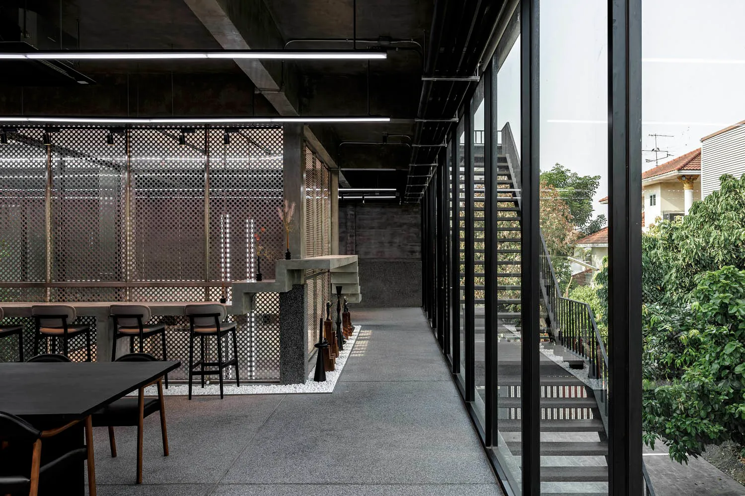 Modern dining space with a staircase, chairs, and a dining table, surrounded by additional seating areas